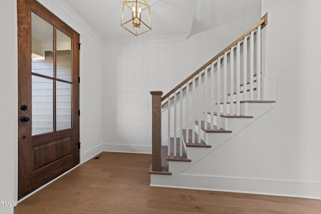 entrance foyer featuring hardwood / wood-style floors, ornamental molding, and an inviting chandelier