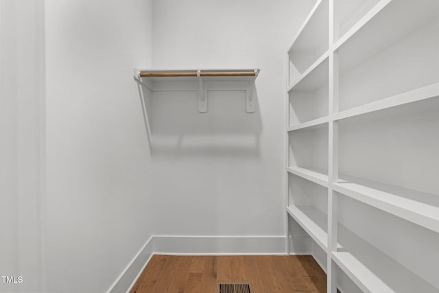 walk in closet with hardwood / wood-style flooring