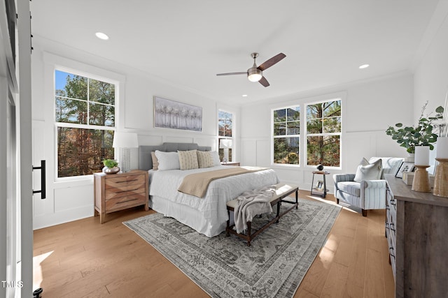 bedroom with light hardwood / wood-style floors, ceiling fan, and crown molding