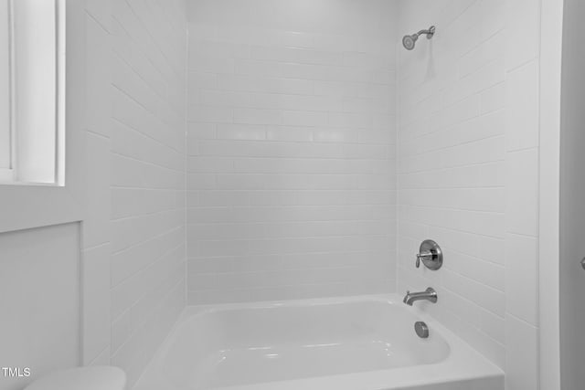 bathroom with toilet and tiled shower / bath