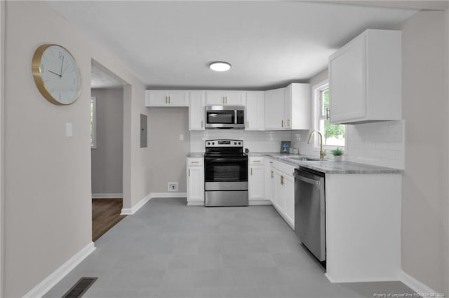 kitchen featuring stainless steel appliances, white cabinets, tasteful backsplash, and light tile floors