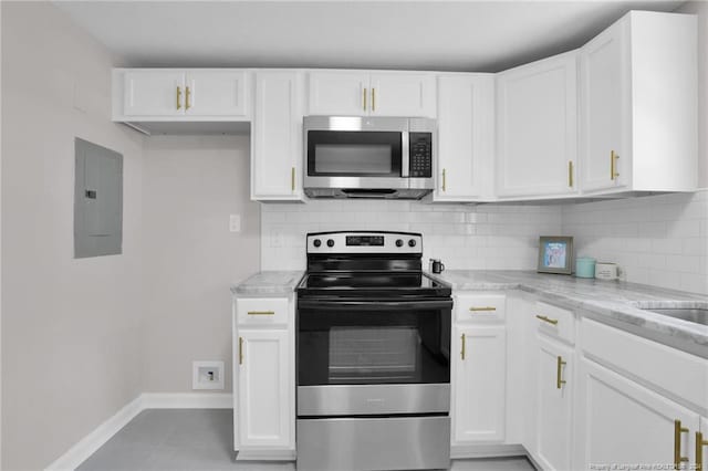 kitchen featuring stainless steel appliances, tile flooring, white cabinetry, and light stone counters