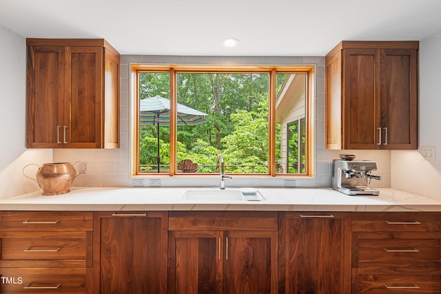 kitchen with tasteful backsplash, sink, and light stone countertops