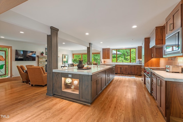 kitchen featuring backsplash, light hardwood / wood-style flooring, high end stove, and a center island with sink