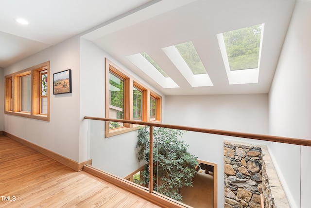 corridor featuring vaulted ceiling and light hardwood / wood-style floors