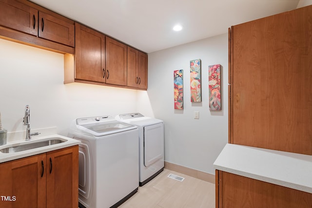 clothes washing area featuring cabinets, separate washer and dryer, and sink