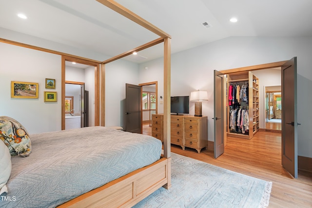 bedroom featuring a closet, lofted ceiling, a spacious closet, and light hardwood / wood-style flooring