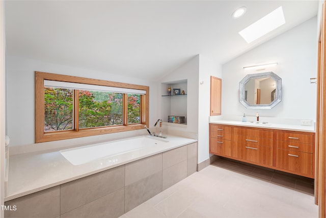 bathroom featuring built in shelves, vanity, tiled tub, vaulted ceiling with skylight, and tile patterned flooring