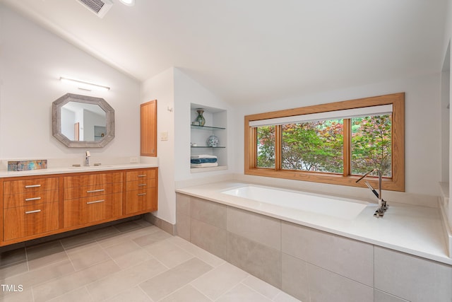 bathroom with lofted ceiling, built in features, vanity, a relaxing tiled tub, and tile patterned floors