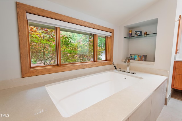 bathroom with vanity, a tub to relax in, tile patterned flooring, and vaulted ceiling