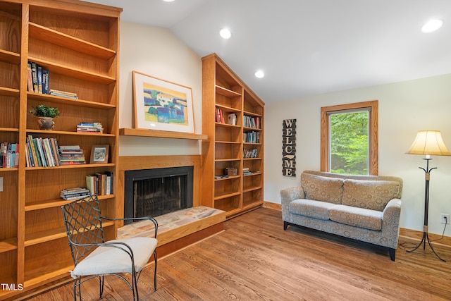 living area with lofted ceiling, hardwood / wood-style floors, and built in shelves