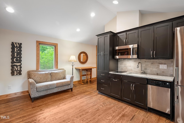 kitchen featuring lofted ceiling, sink, stainless steel appliances, and light hardwood / wood-style floors