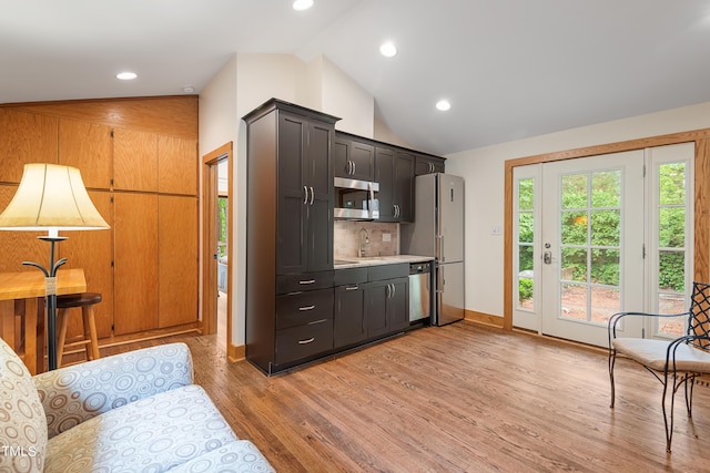 kitchen with appliances with stainless steel finishes, vaulted ceiling, hardwood / wood-style floors, and a wealth of natural light