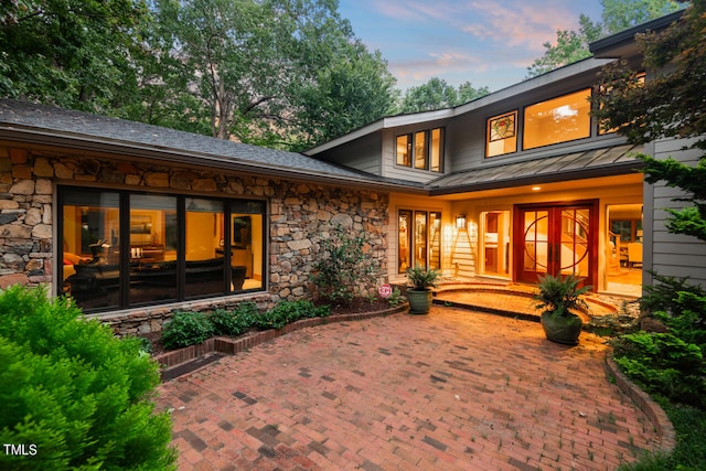 back house at dusk featuring a patio