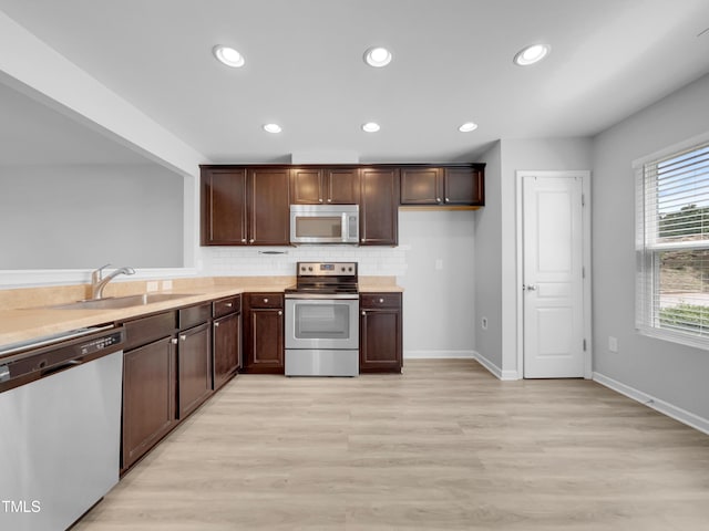 kitchen featuring backsplash, dark brown cabinets, stainless steel appliances, sink, and light hardwood / wood-style floors