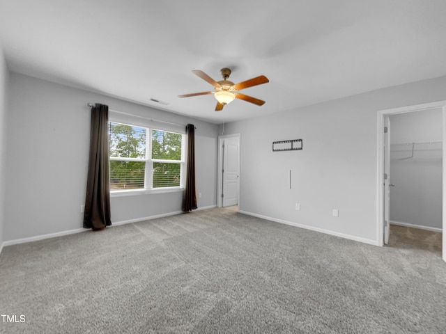 unfurnished bedroom featuring carpet flooring, a closet, a spacious closet, and ceiling fan