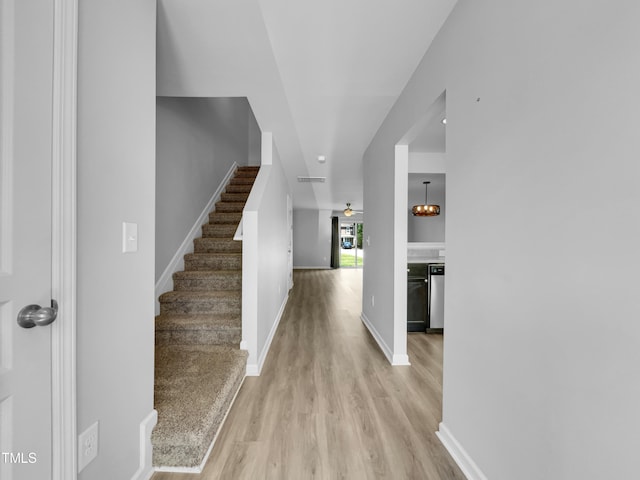 foyer with ceiling fan with notable chandelier and light hardwood / wood-style floors