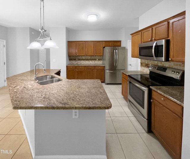 kitchen with pendant lighting, stainless steel appliances, a center island with sink, and sink