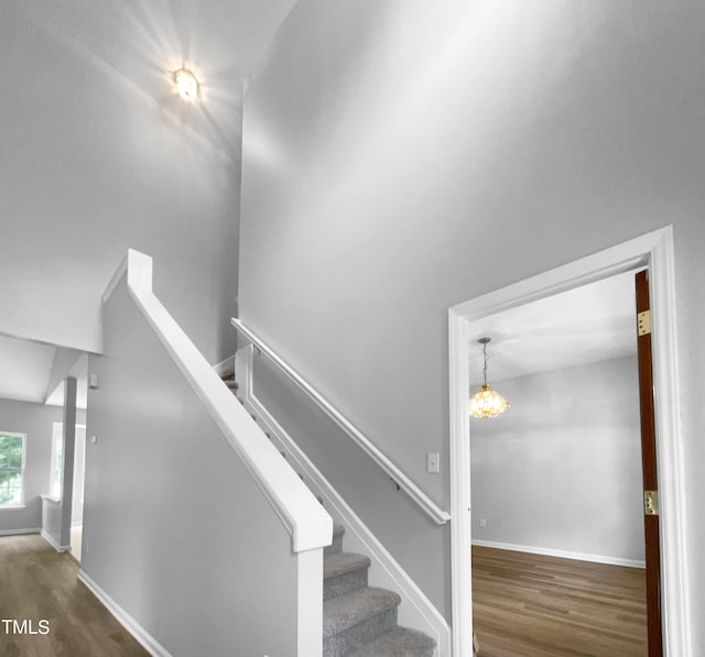 stairway featuring wood-type flooring and a notable chandelier