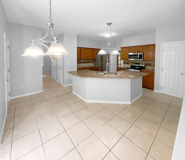 kitchen featuring pendant lighting, backsplash, light stone countertops, appliances with stainless steel finishes, and a large island