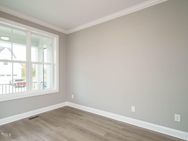 spare room featuring crown molding and light hardwood / wood-style floors