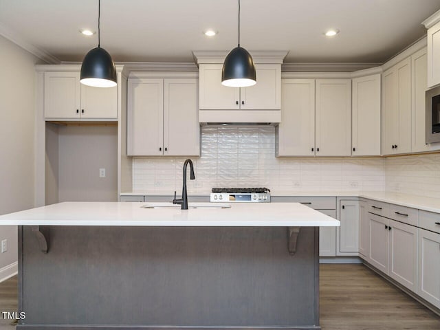 kitchen with decorative light fixtures, tasteful backsplash, an island with sink, and dark wood-type flooring