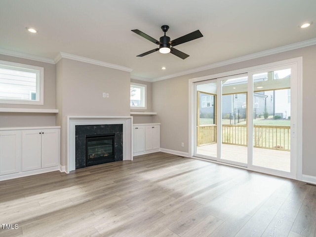 unfurnished living room featuring a fireplace, light hardwood / wood-style floors, plenty of natural light, and ornamental molding