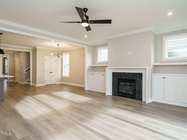 unfurnished living room with ceiling fan, light hardwood / wood-style floors, ornamental molding, and a premium fireplace