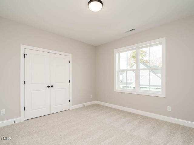 unfurnished bedroom featuring a closet and light colored carpet