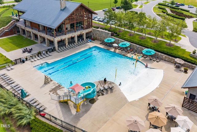 view of pool with a water slide and a patio