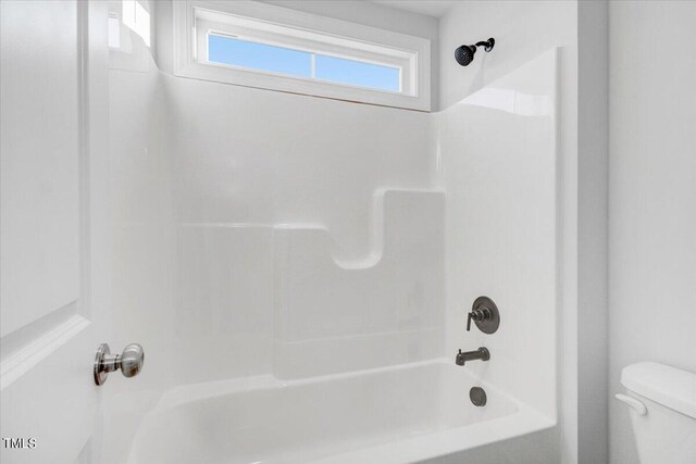 bathroom featuring bathtub / shower combination and toilet