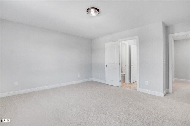 unfurnished bedroom featuring ensuite bathroom and light colored carpet