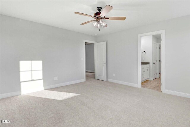 unfurnished bedroom with ceiling fan, ensuite bath, and light carpet