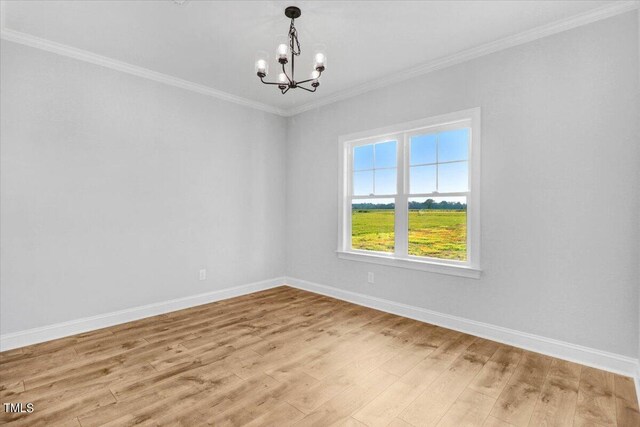 spare room featuring an inviting chandelier, light hardwood / wood-style flooring, and ornamental molding