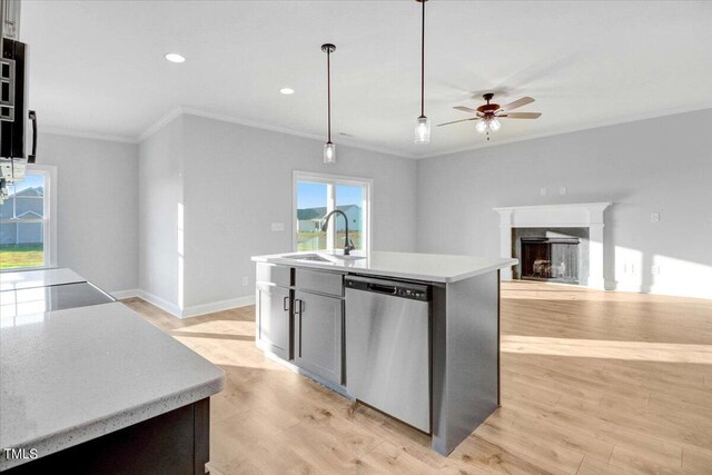 kitchen featuring sink, hanging light fixtures, a center island with sink, dishwasher, and a high end fireplace