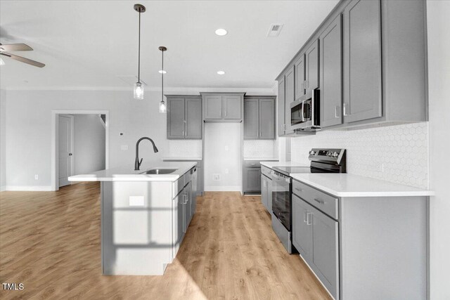 kitchen featuring gray cabinets, sink, hanging light fixtures, stainless steel appliances, and a center island with sink