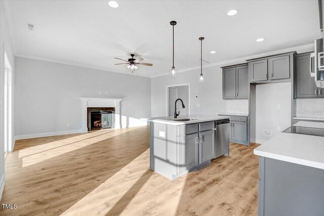 kitchen featuring sink, gray cabinetry, hanging light fixtures, an island with sink, and stainless steel dishwasher