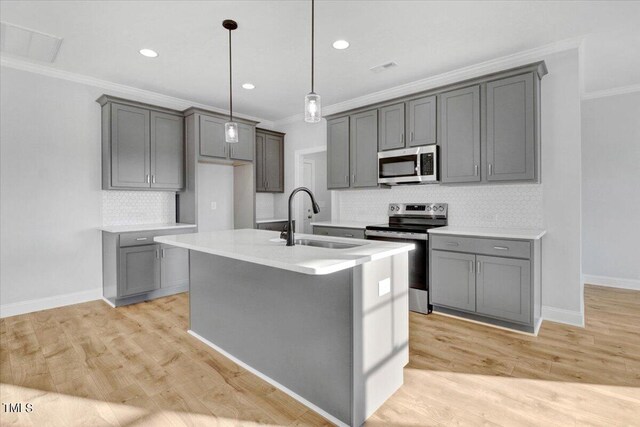 kitchen featuring sink, gray cabinets, stainless steel appliances, and a center island with sink