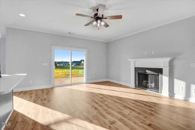 unfurnished living room featuring ceiling fan, ornamental molding, and light wood-type flooring