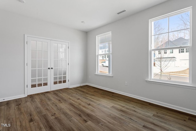 spare room with dark wood-style floors, visible vents, and baseboards