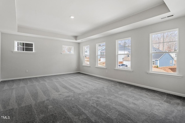 spare room featuring a tray ceiling, carpet, visible vents, and baseboards