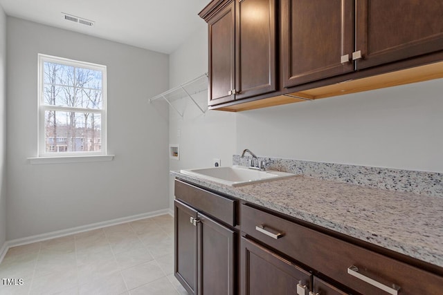 washroom featuring washer hookup, visible vents, cabinet space, a sink, and baseboards