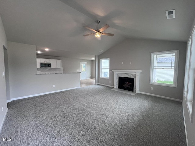 unfurnished living room with a premium fireplace, carpet flooring, a ceiling fan, and visible vents