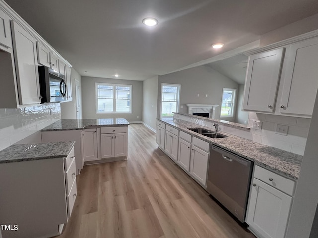 kitchen featuring a peninsula, appliances with stainless steel finishes, a sink, and light stone countertops