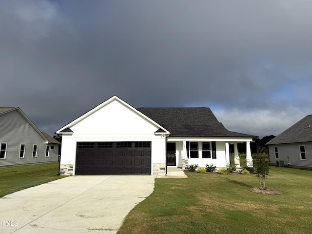 view of front of property with stone siding, a front lawn, an attached garage, a shingled roof, and concrete driveway
