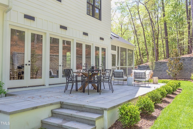 wooden deck with a sunroom, french doors, and a patio