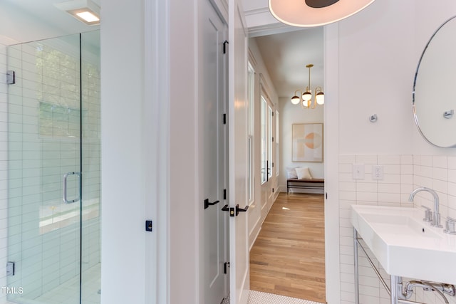 bathroom with sink, tile walls, walk in shower, and a notable chandelier