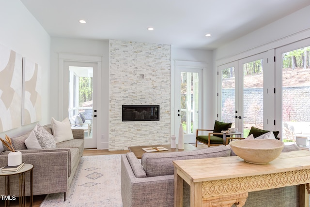 living room with light wood-type flooring, french doors, and a fireplace