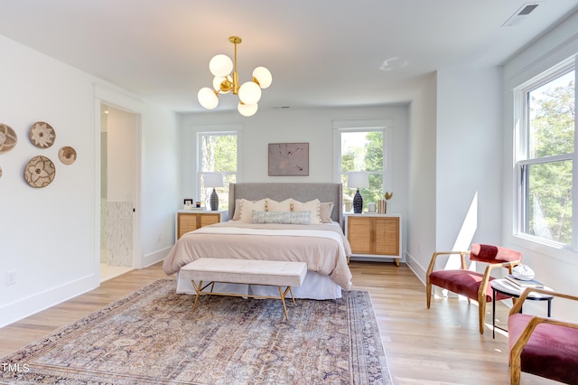 bedroom with multiple windows, light hardwood / wood-style flooring, and a chandelier