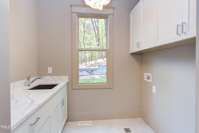 clothes washing area featuring cabinets, sink, light tile patterned flooring, and washer hookup